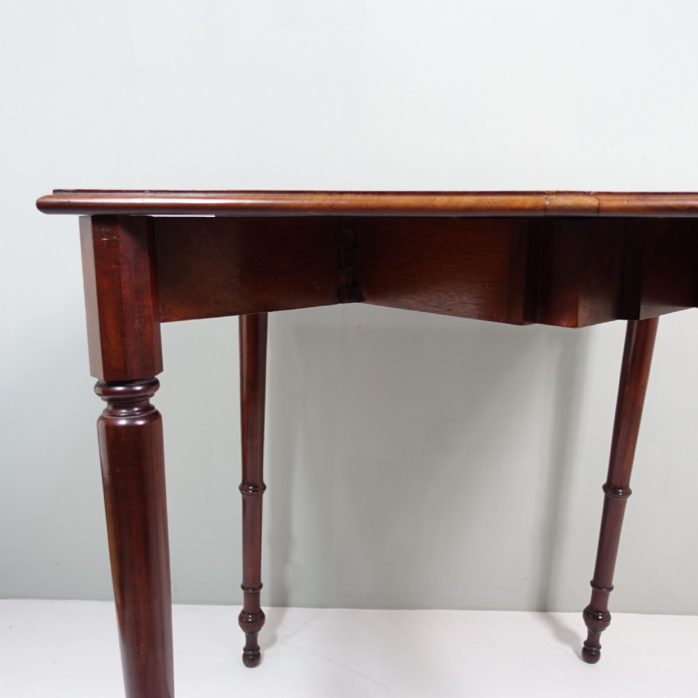 A 19th-century mahogany side table featuring four slender turned legs and triangular hinged drop leaves on each side. View VII
