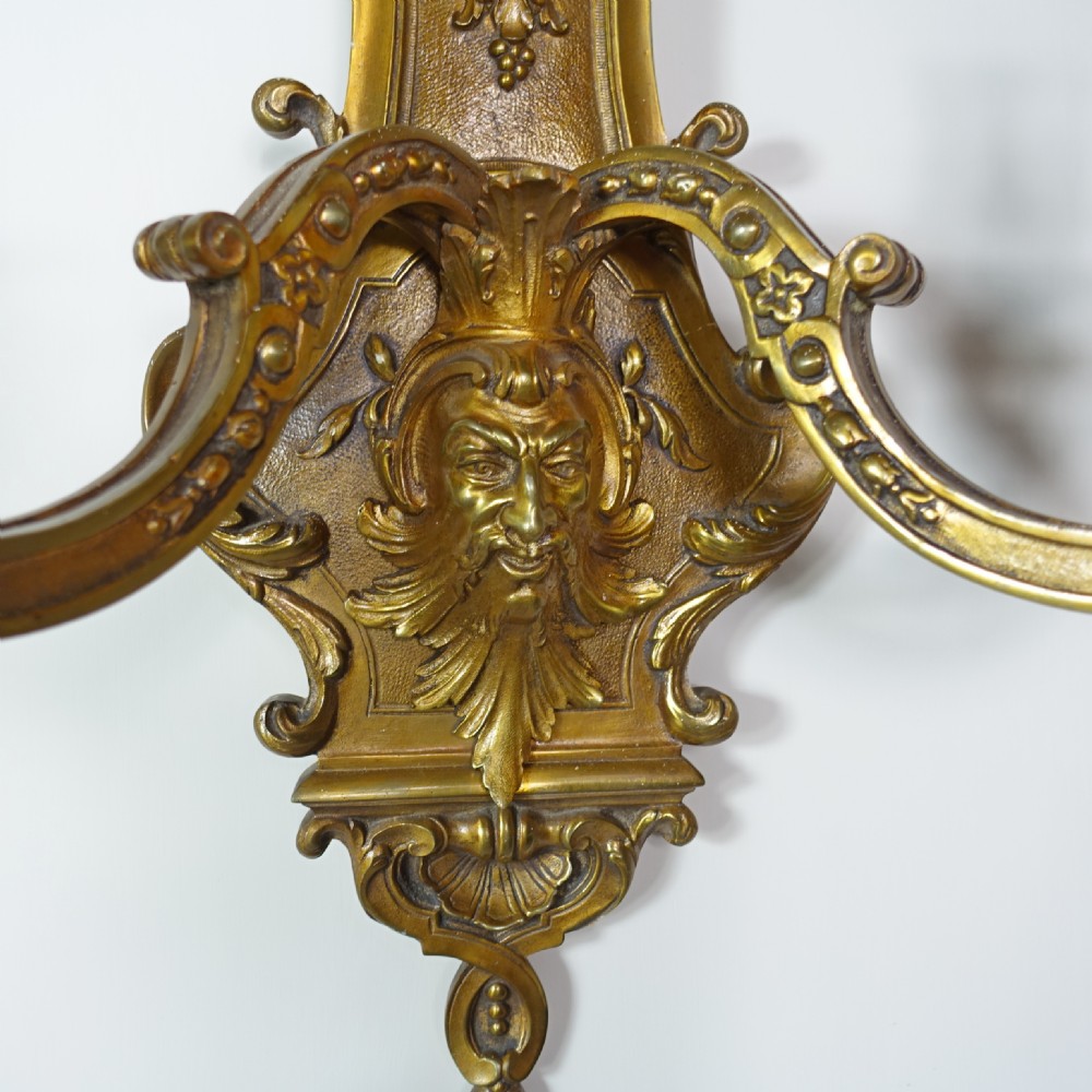 A pair of 19th-century gilt bronze wall sconces, each featuring two scrolling branches, central mascaron face motifs, and shell finials. View II