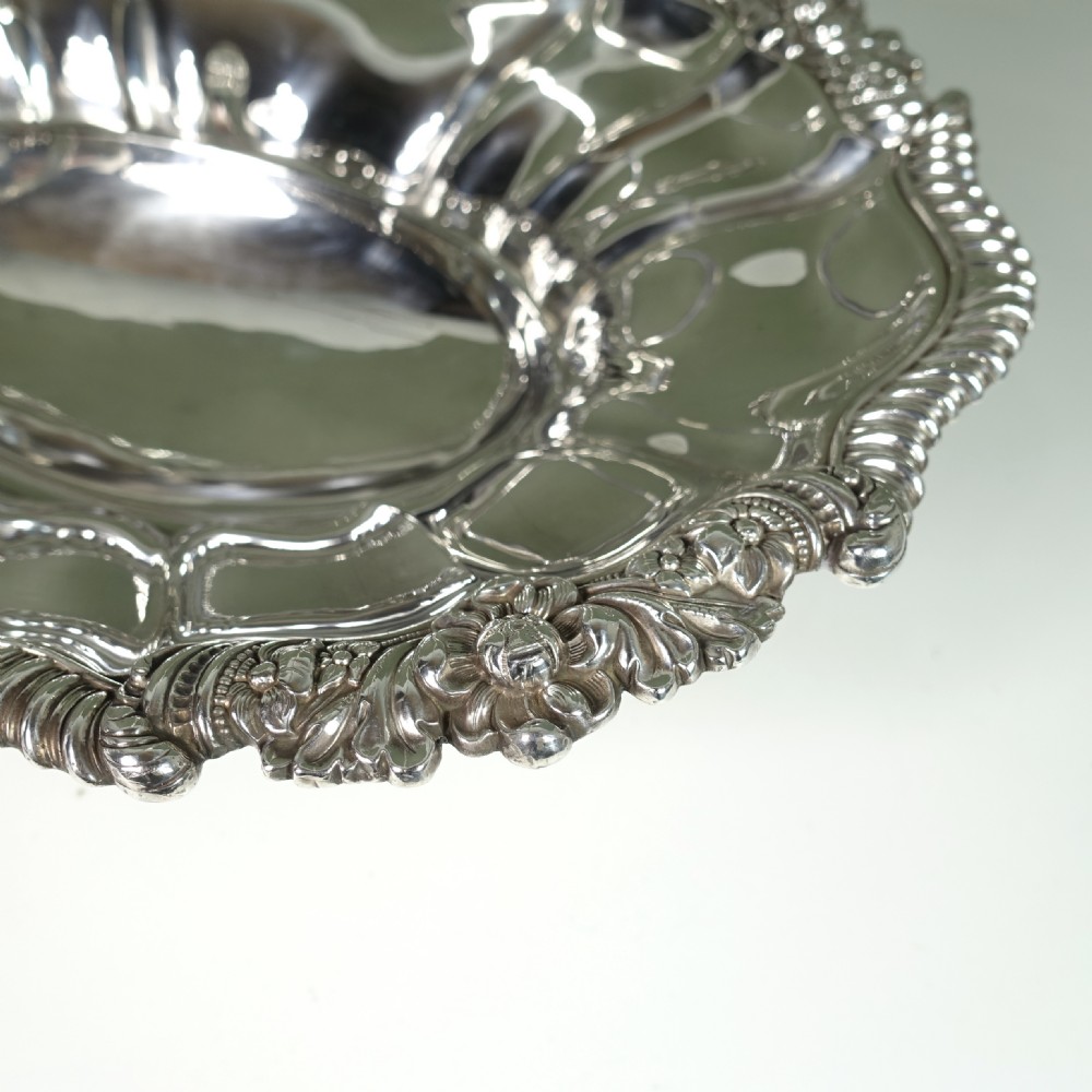 A nineteenth-century silver-plated oval basket featuring fluted side panels, a decorative chased rim, a pedestal base, and an arched swing handle. View V