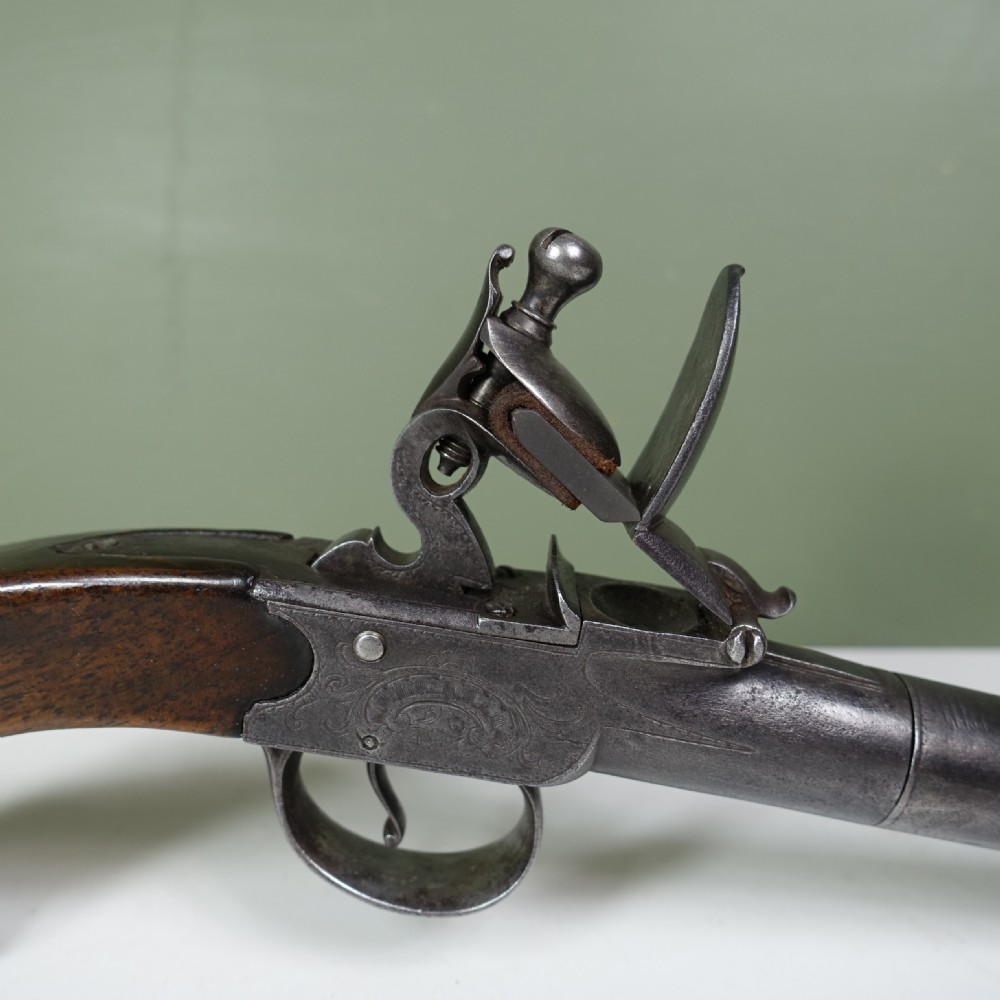An 18th-century steel box-lock flintlock pistol featuring an engraved lockplate, steel trigger guard, and polished dark walnut grip. View V