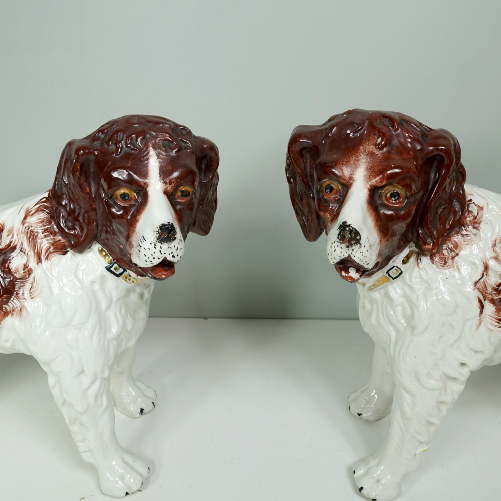 A pair of 19th-century earthenware Staffordshire standing dog figurines with white bodies and hand-painted brown patches. View V