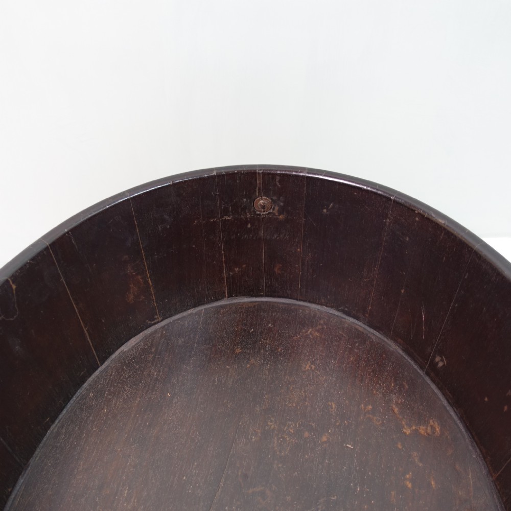 An 18th-century oval mahogany wine cooler featuring coopered wooden staves held together by two wide brass bands and fitted with side brass handles. View V