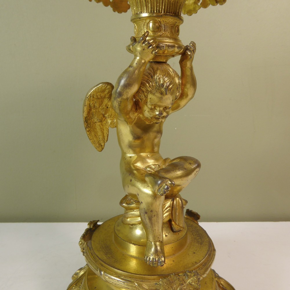 A 19th-century gilt bronze ormolu tazza base featuring a winged cherub figure supporting a fluted capital above a rococo scrolled pedestal. View IV
