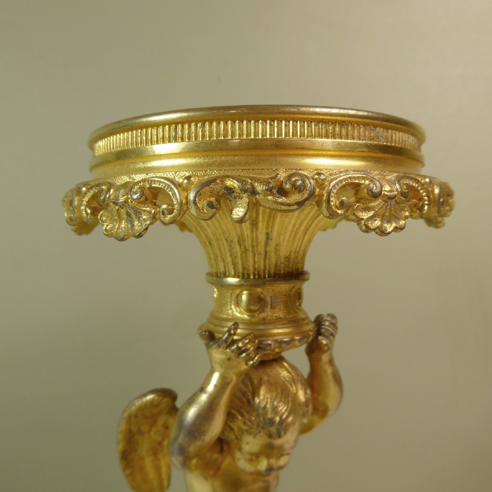 A 19th-century gilt bronze ormolu tazza base featuring a winged cherub figure supporting a fluted capital above a rococo scrolled pedestal. View V