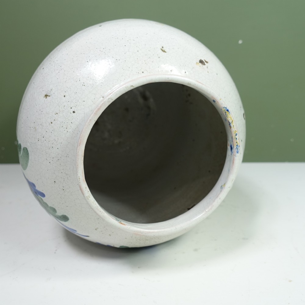An 18th-century tin-glazed earthenware apothecary jar in off-white, hand-painted with green leaves, a yellow ribbon bow, and Latin text. View VIII
