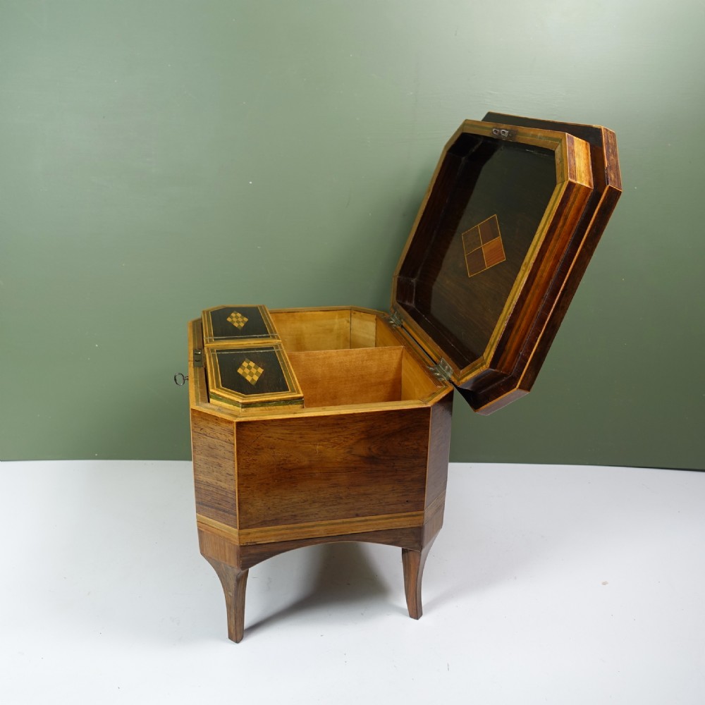 An early nineteenth-century wooden caddy featuring geometric parquetry inlay on the lid, canted corners, crossbanded sides, and integrated tapered legs. View VI
