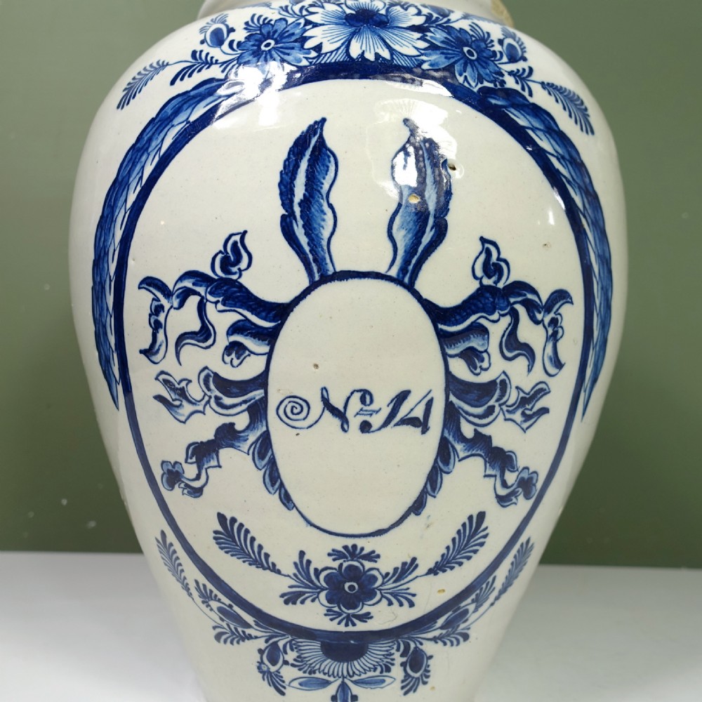 An 18th-century blue and white tin-glazed earthenware Delft jar featuring hand-painted floral cartouche decoration numbered No. 14, fitted with a brass lid. View VIII