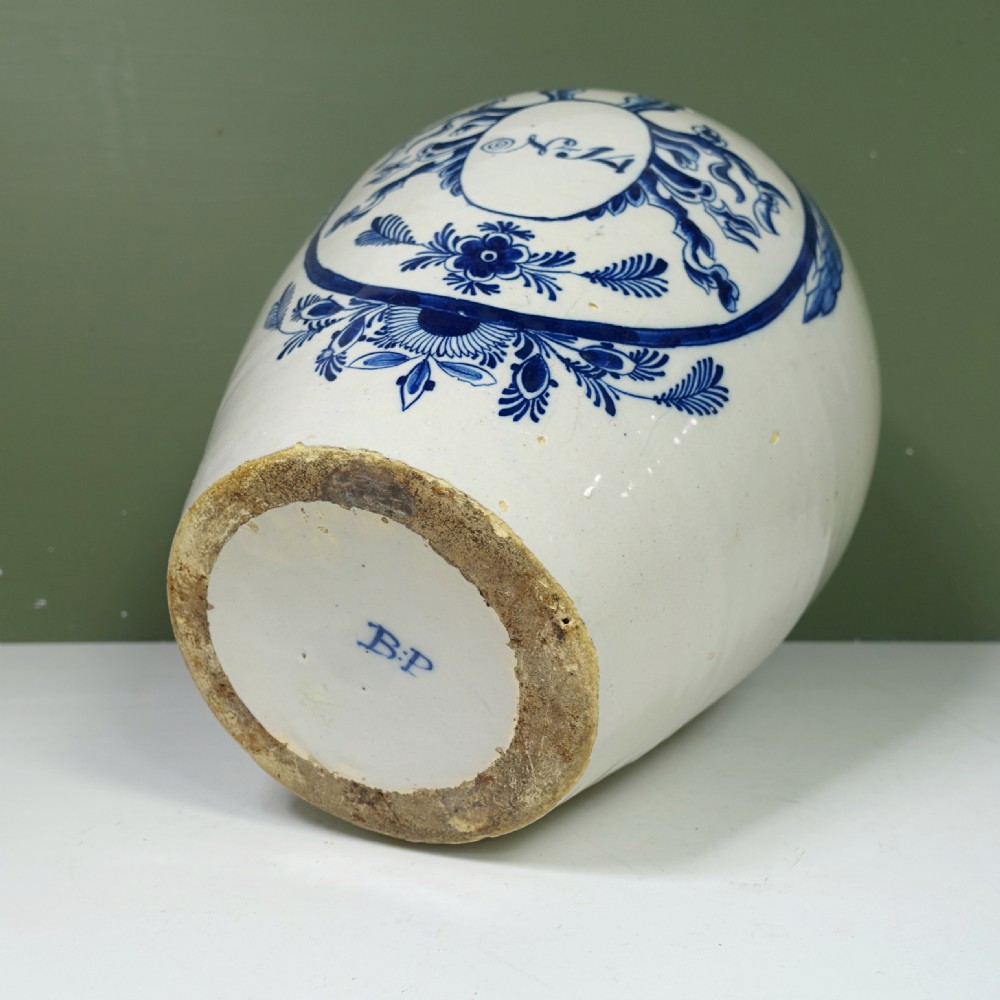 An 18th-century blue and white tin-glazed earthenware Delft jar featuring hand-painted floral cartouche decoration numbered No. 14, fitted with a brass lid. View IX