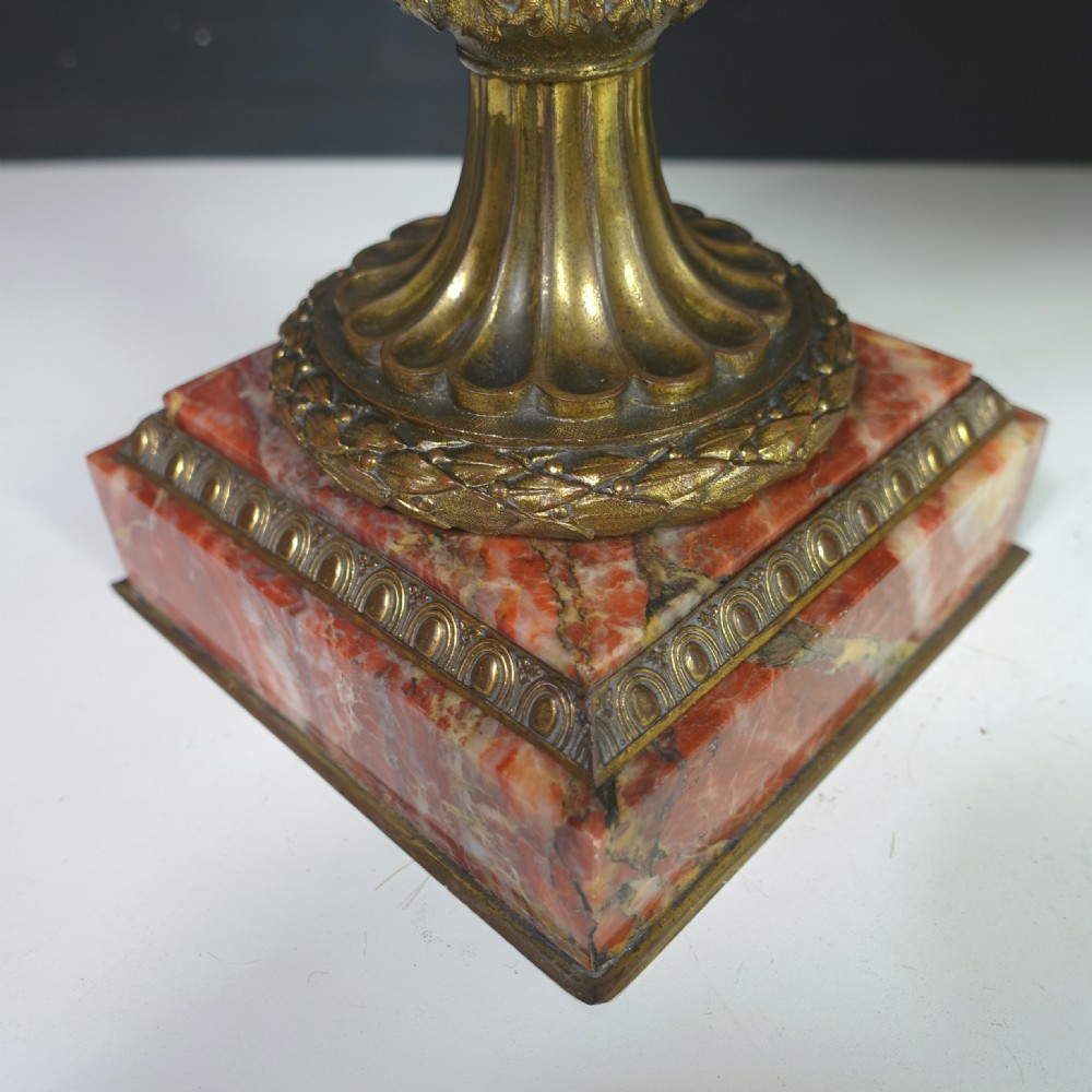 A pair of 19th-century French red veined marble vases with gilded bronze handles and decorative leaf finials set on square plinth bases. View V
