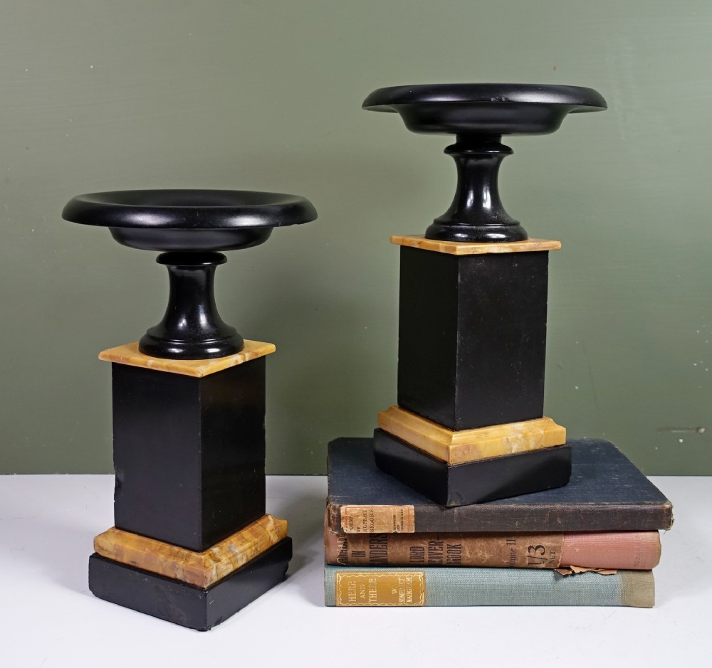 A pair of 19th-century Neoclassical black marble tazzas set on square pedestal bases accented with yellow sienna marble layers.