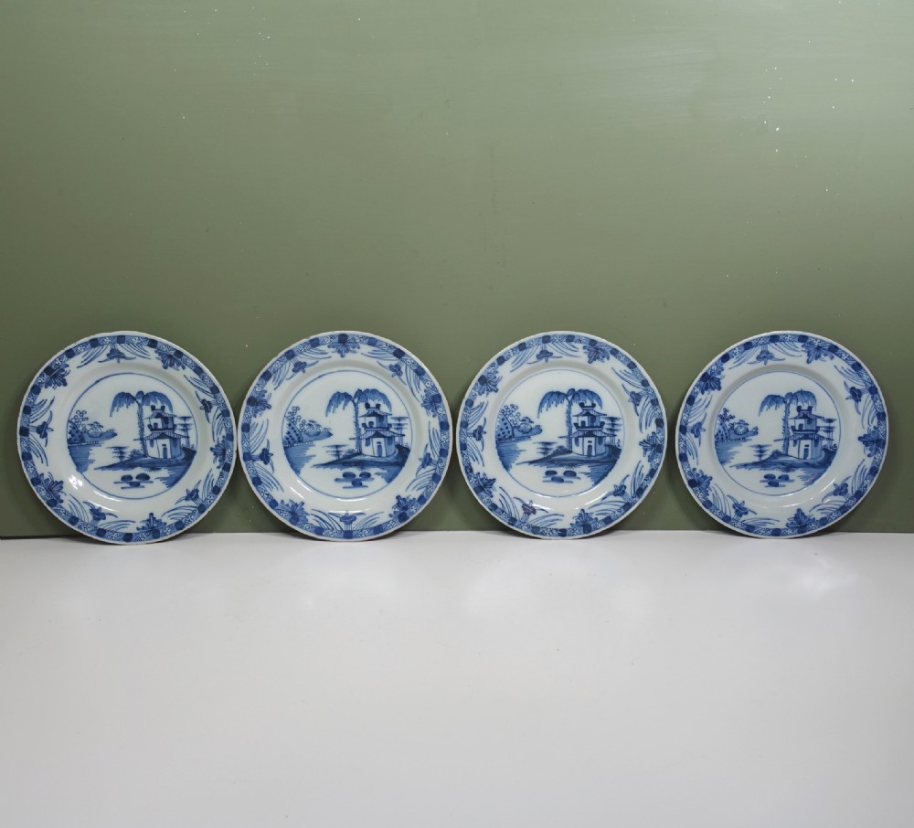 A set of four 18th-century tin-glazed earthenware delft plates, hand-painted in cobalt blue with chinoiserie pagoda landscapes and decorative rims on a pale ground.