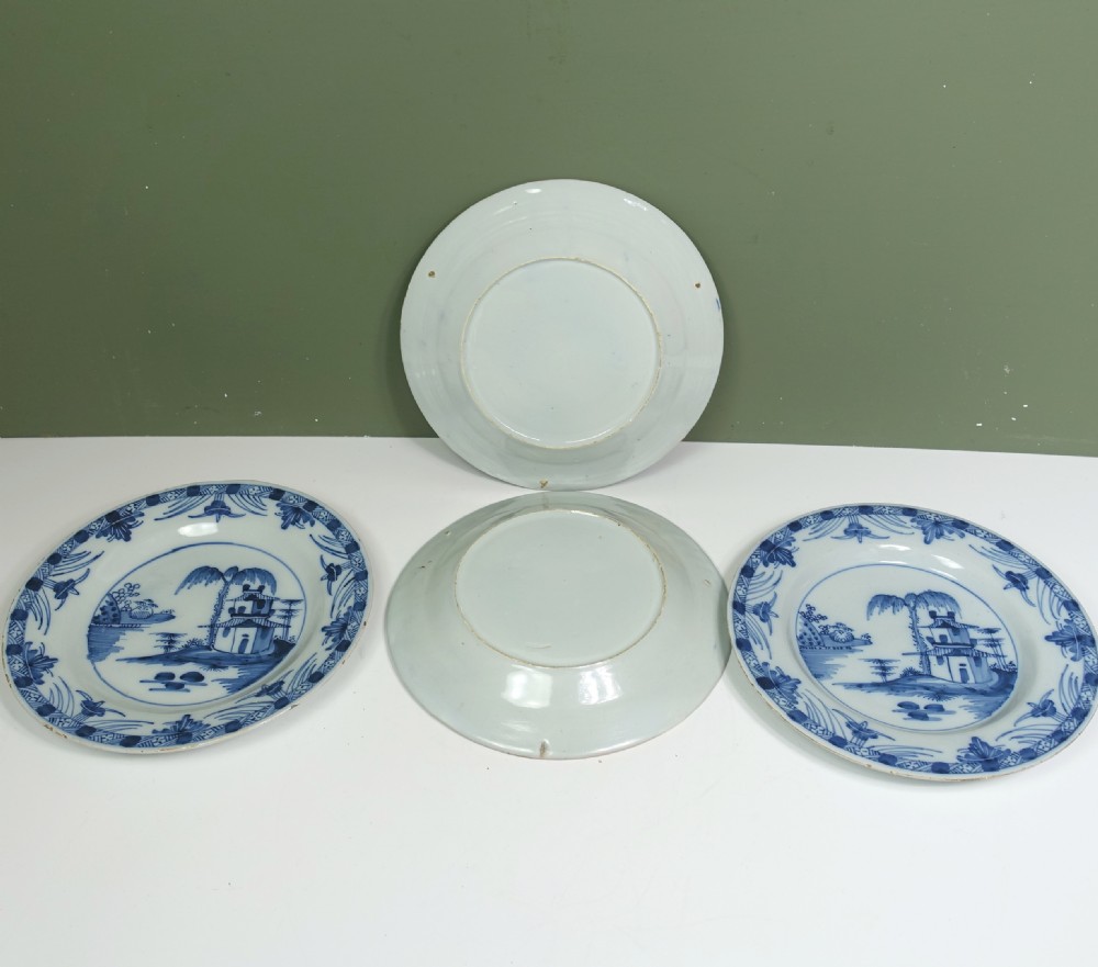 A set of four 18th-century tin-glazed earthenware delft plates, hand-painted in cobalt blue with chinoiserie pagoda landscapes and decorative rims on a pale ground. View III