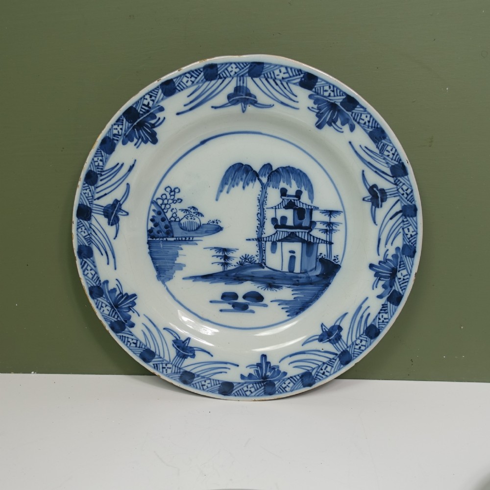 A set of four 18th-century tin-glazed earthenware delft plates, hand-painted in cobalt blue with chinoiserie pagoda landscapes and decorative rims on a pale ground. View V