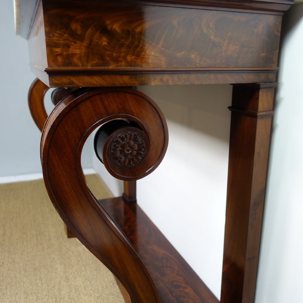 A 19th-century mahogany console table featuring a white marble top, scrolled front supports terminating in carved paw feet, flame mahogany veneer, and a plinth base. View V