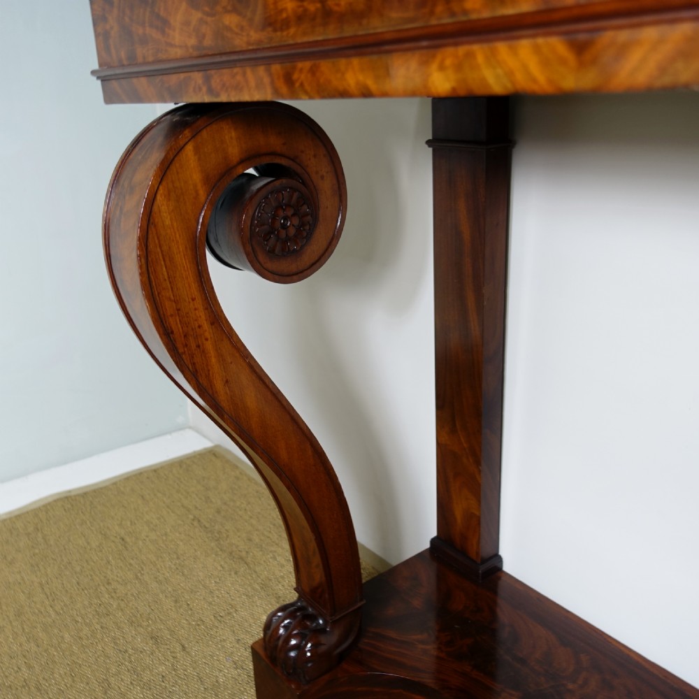 A 19th-century mahogany console table featuring a white marble top, scrolled front supports terminating in carved paw feet, flame mahogany veneer, and a plinth base. View VII