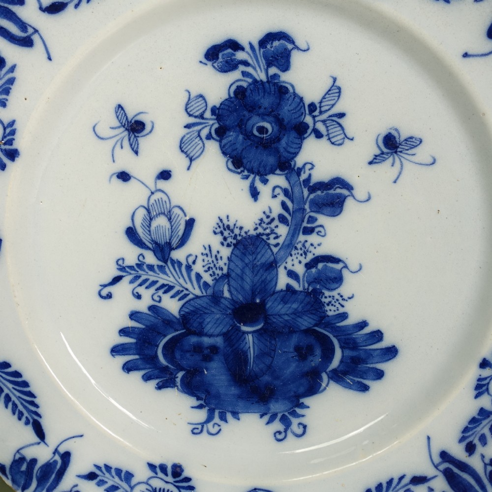 An 18th-century circular tin-glazed earthenware charger plate featuring hand-painted cobalt blue floral motifs and an ornate patterned rim. View II