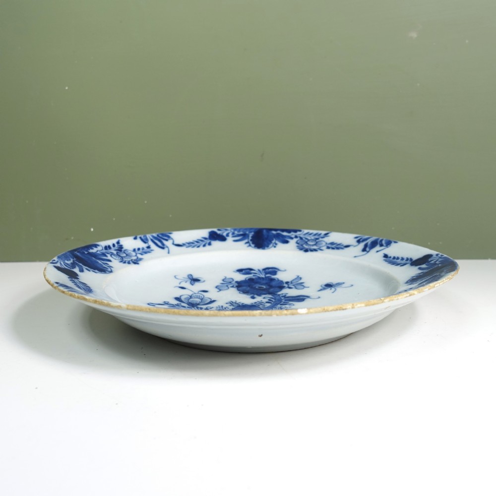 An 18th-century circular tin-glazed earthenware charger plate featuring hand-painted cobalt blue floral motifs and an ornate patterned rim. View V