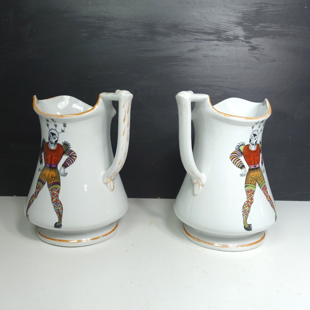 A pair of white Victorian ironstone puzzle jugs featuring hand-painted jester figures in colourful attire. View VII