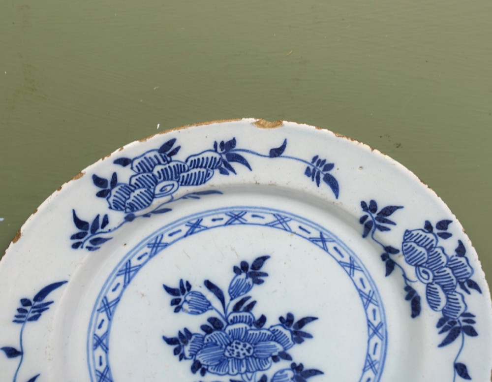 Pair of circular 18th-century tin-glazed earthenware Delft plates decorated with central cobalt blue hand-painted floral motifs and geometric rim borders. View III