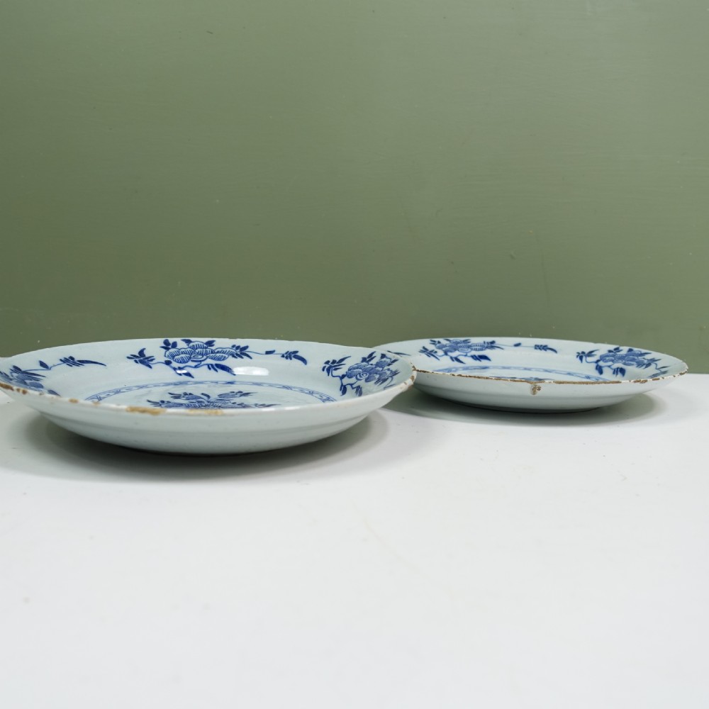 Pair of circular 18th-century tin-glazed earthenware Delft plates decorated with central cobalt blue hand-painted floral motifs and geometric rim borders. View VI