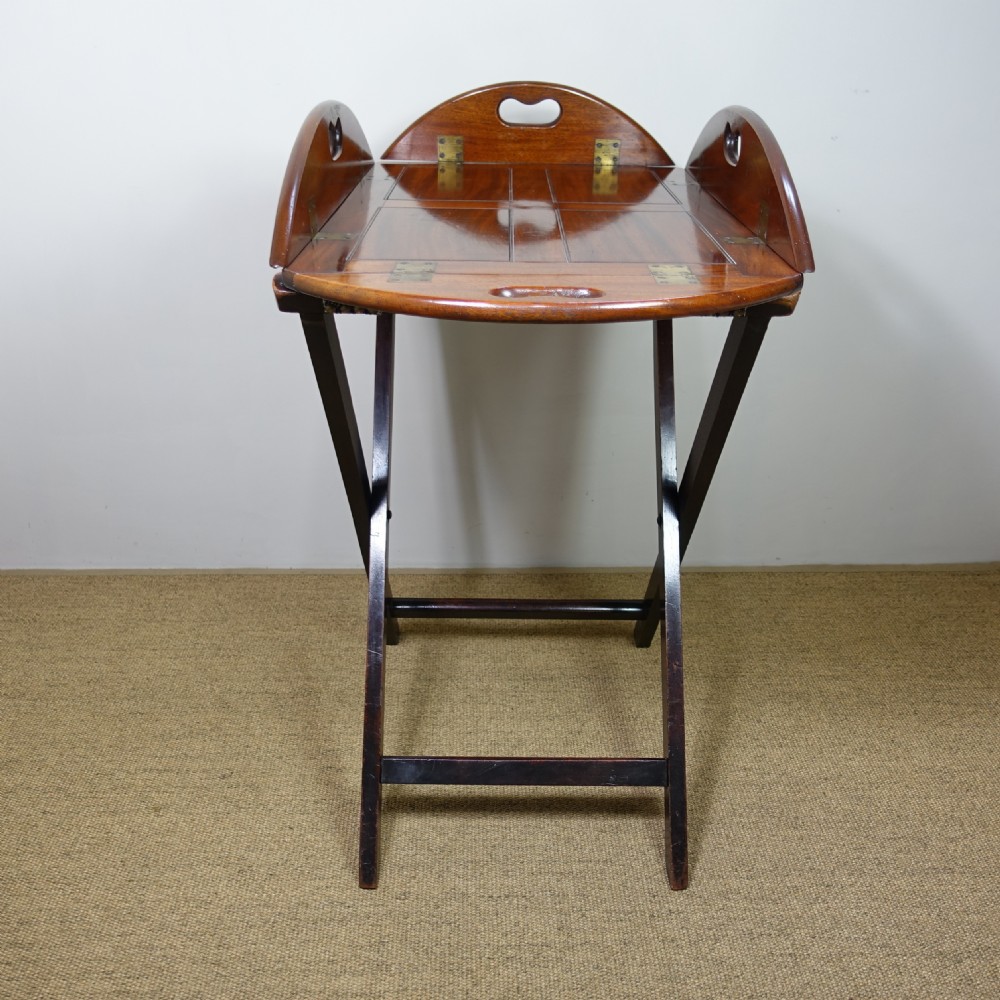 A George III mahogany butlers tray with hinged gallery sides resting on a folding cross-frame stand. View V