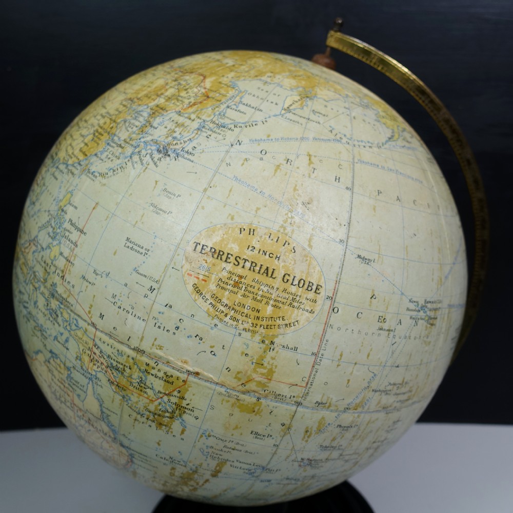 A vintage terrestrial globe featuring printed paper maps on a brass semi-meridian arc, mounted to a dark circular turned wooden base. View III