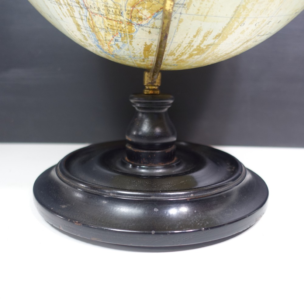 A vintage terrestrial globe featuring printed paper maps on a brass semi-meridian arc, mounted to a dark circular turned wooden base. View VI