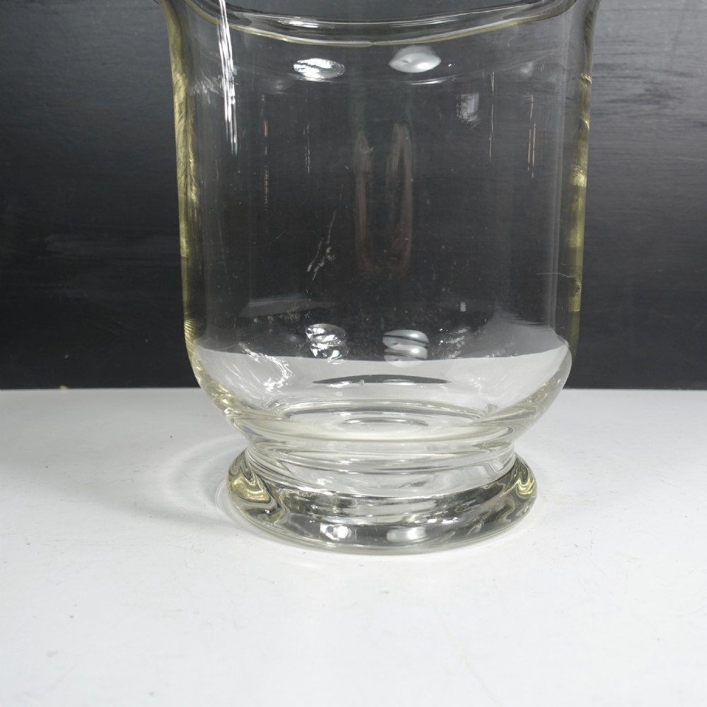 A large clear blown glass vase featuring a flared rim, a contoured body, and a circular moulded base. View V