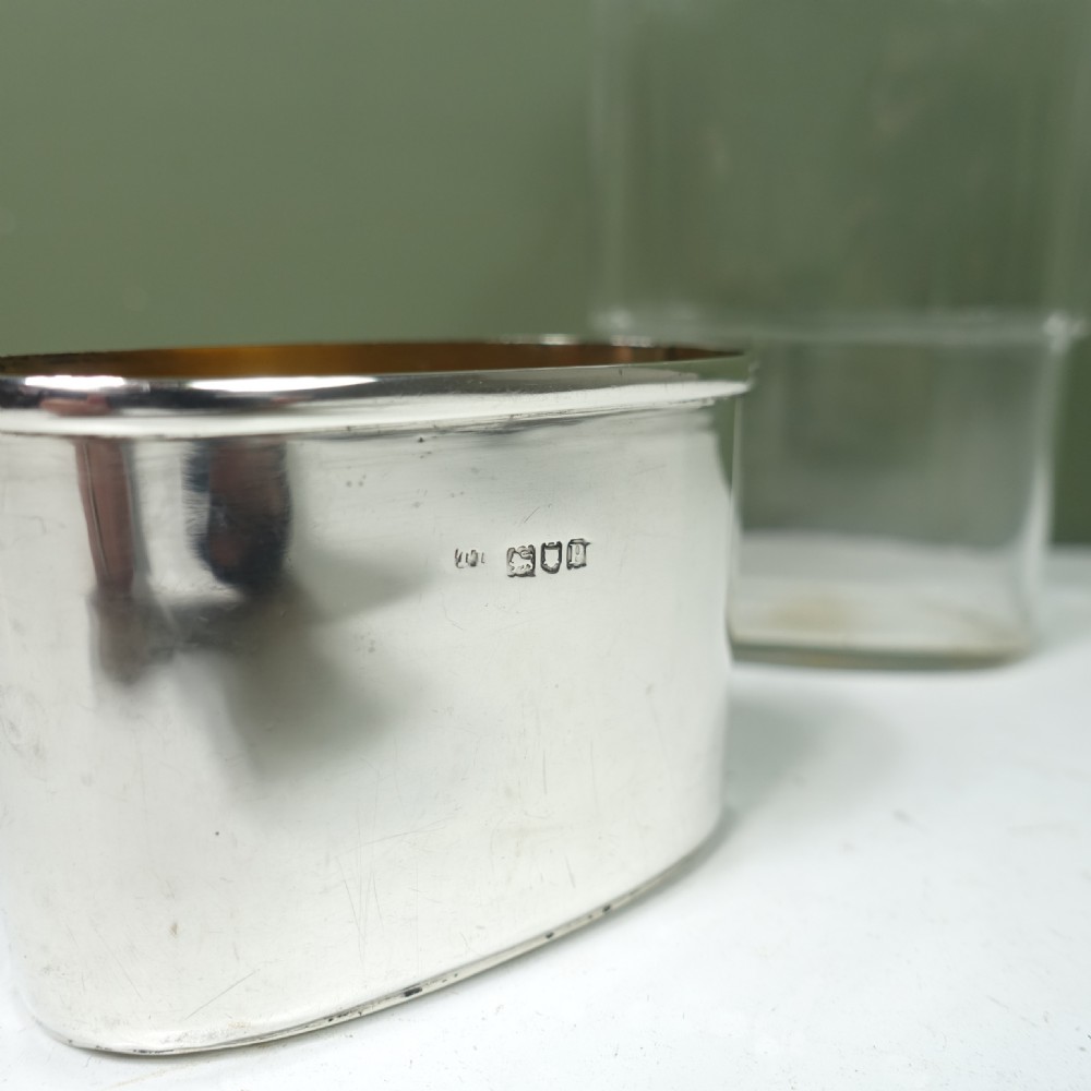 An Edwardian sterling silver and cut glass hip flask featuring a hallmarked removable silver cup base and a silver hinged bayonet cap. View VI