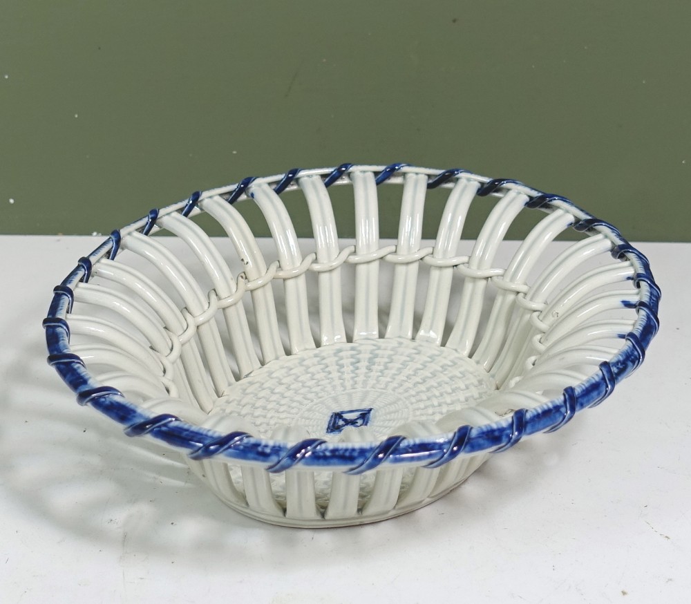 An early nineteenth-century oval pearlware ceramic basket featuring openwork lattice walls, a woven interior base, and a blue twisted rope rim.