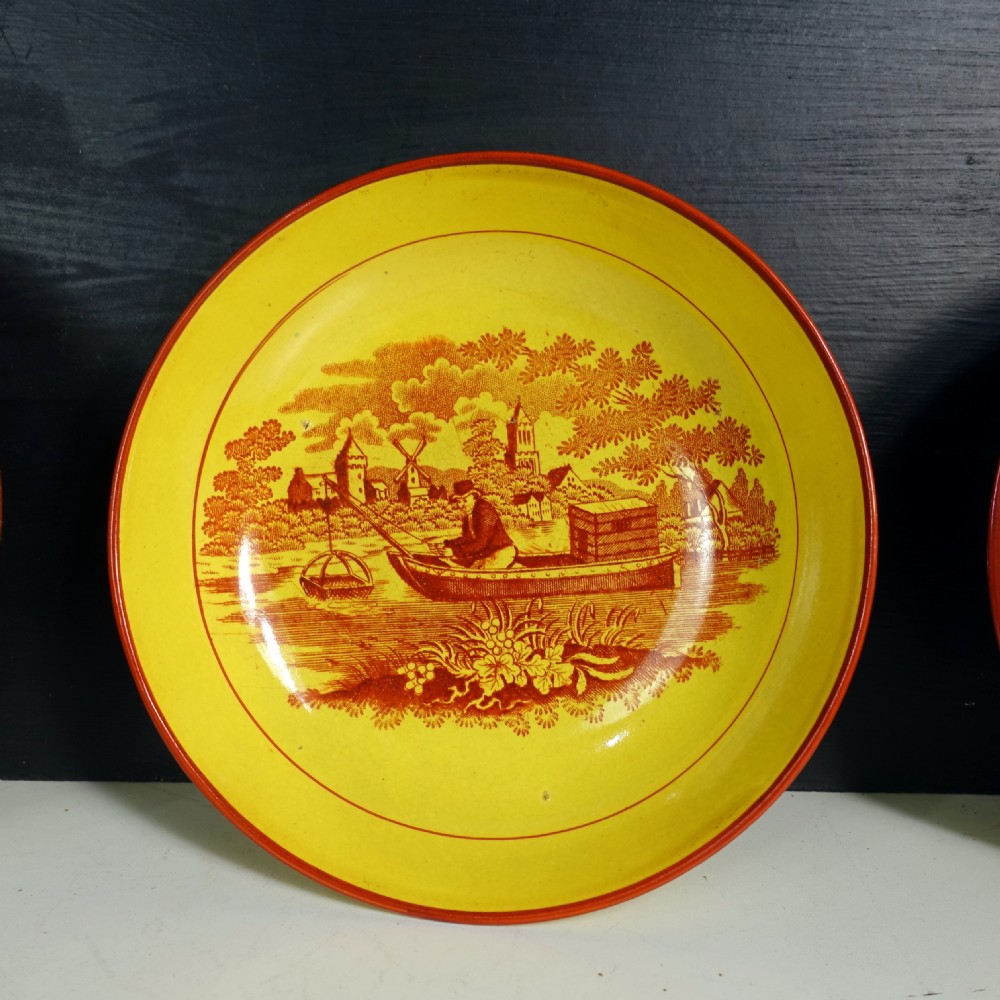 Eight yellow earthenware tea bowls with matching saucers decorated in reddish-brown printed pastoral landscapes. View VI