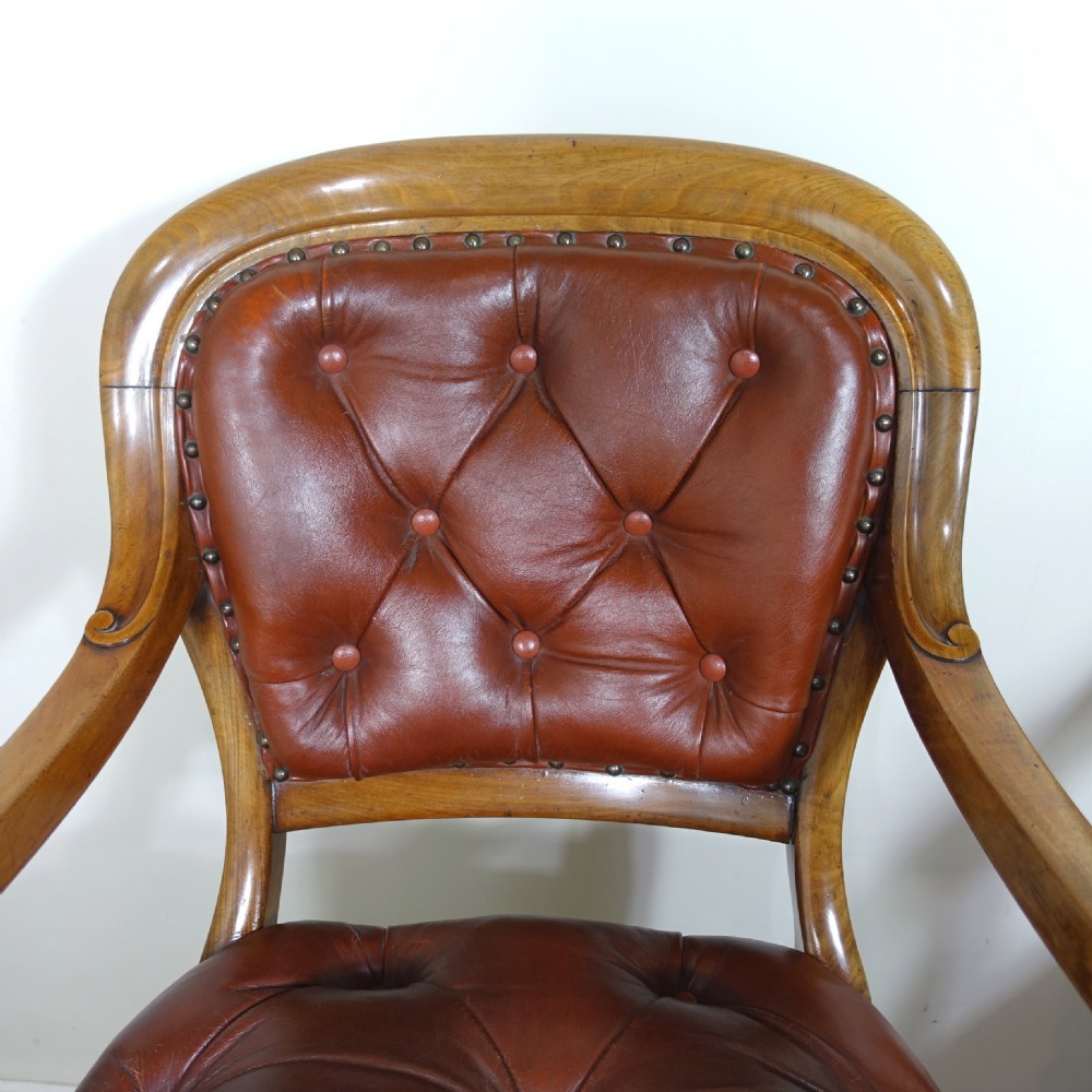 A pair of 19th-century mahogany armchairs upholstered in deep-buttoned reddish-brown leather with brass stud detail and turned front legs on castors. View III