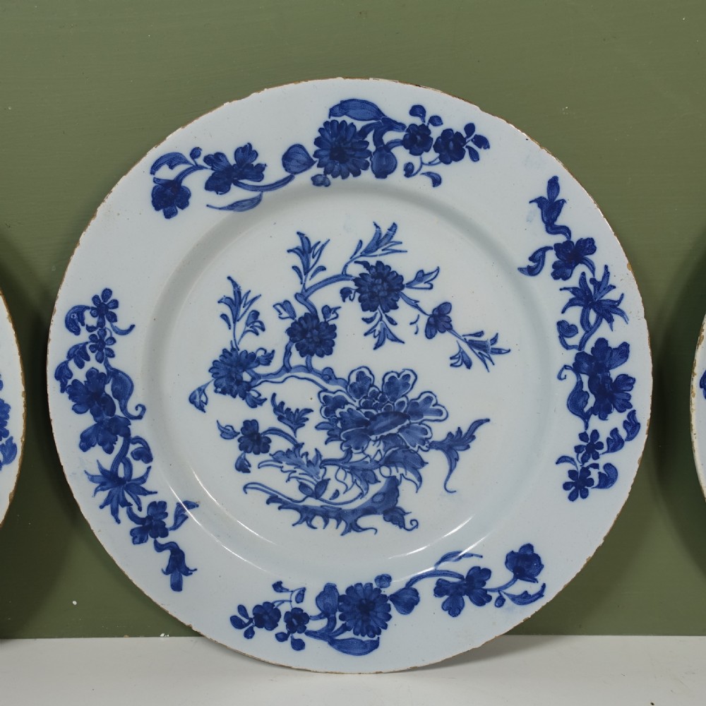 A set of three circular 18th-century tin-glazed earthenware plates decorated with hand-painted cobalt blue floral and chinoiserie designs on a white ground. View III
