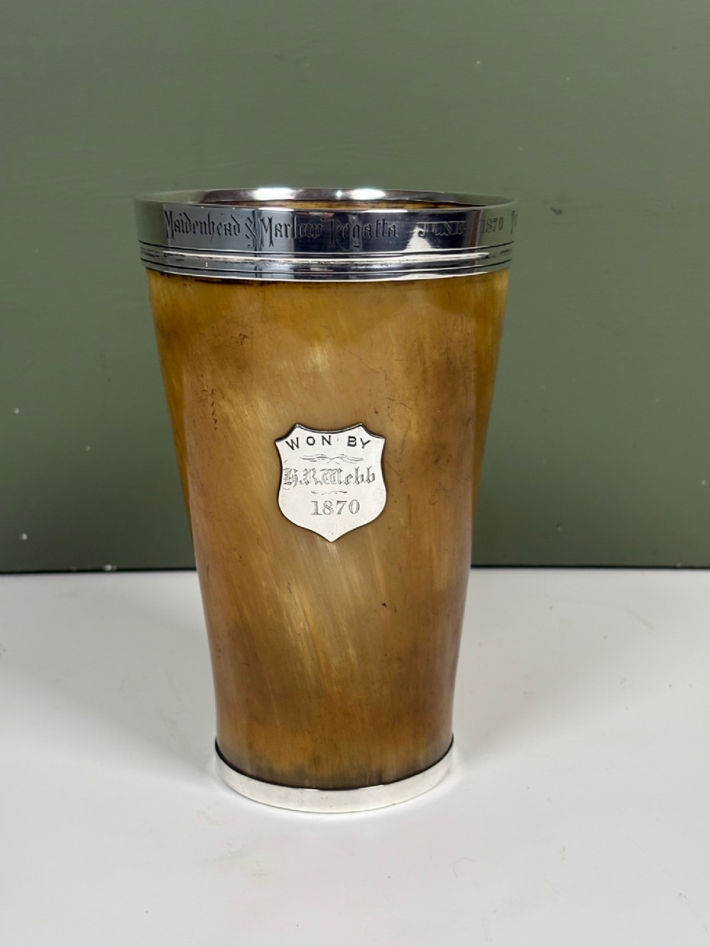 A tapered Victorian horn beaker featuring an engraved silver rim and an engraved silver shield cartouche on the front.