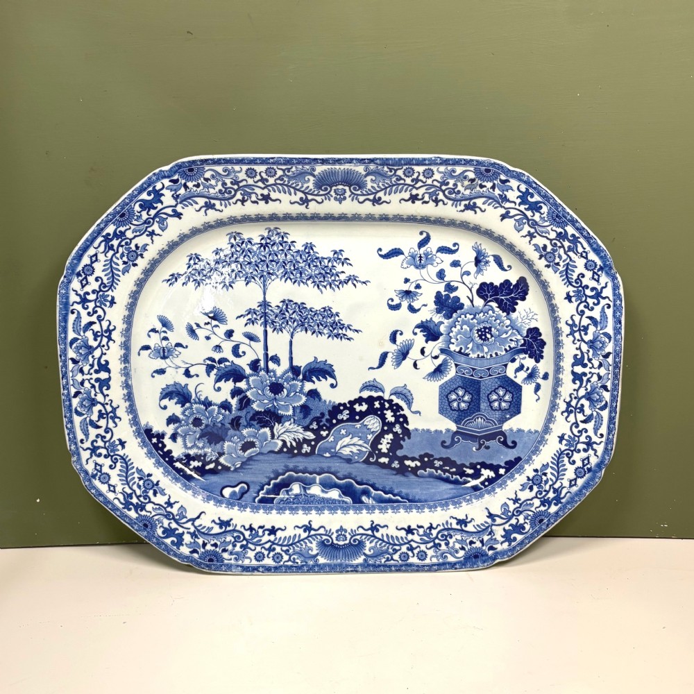 An octagonal nineteenth-century earthenware meat platter decorated with a blue and white Chinoiserie floral landscape and decorative border.