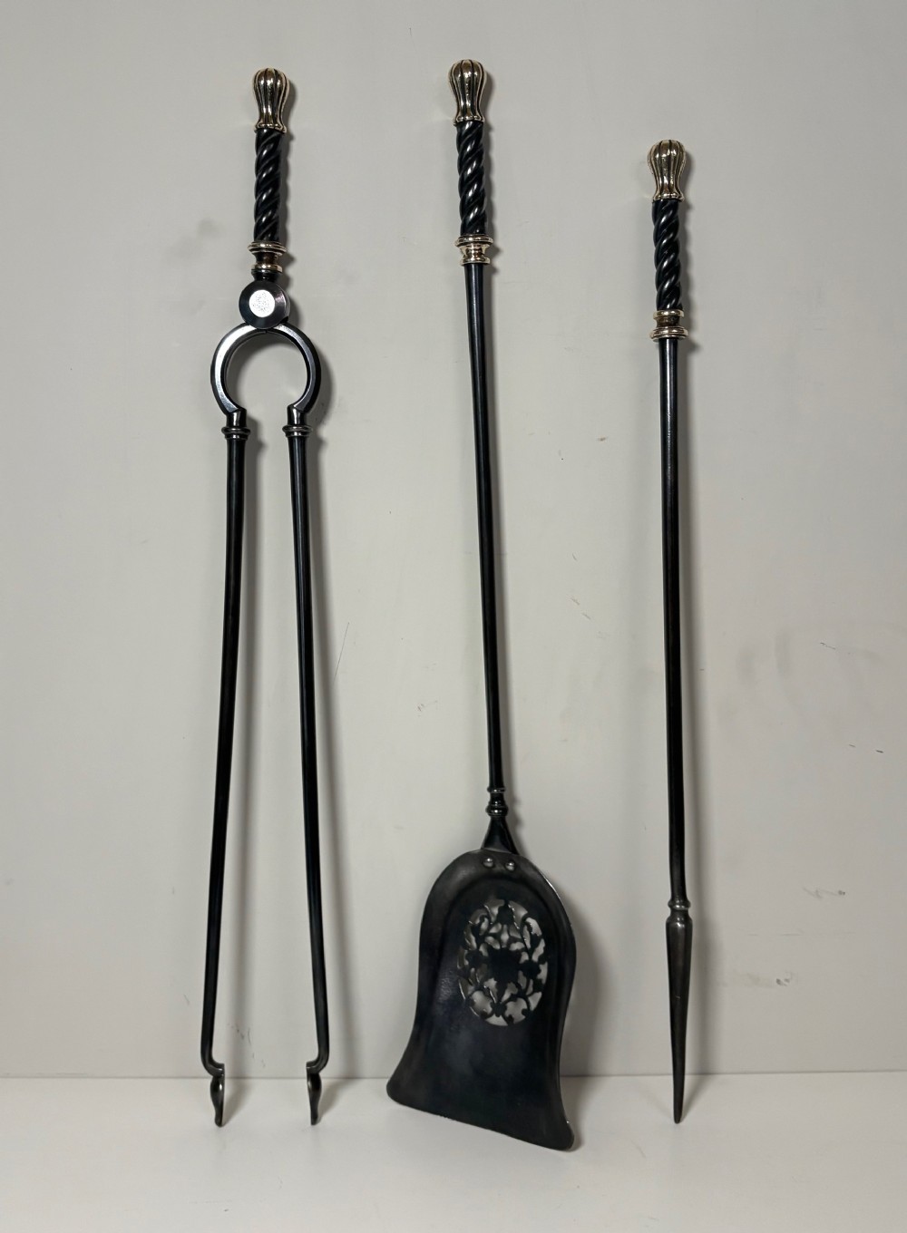 A set of three early nineteenth-century dark steel fire tools featuring twisted handles and fluted brass finials.