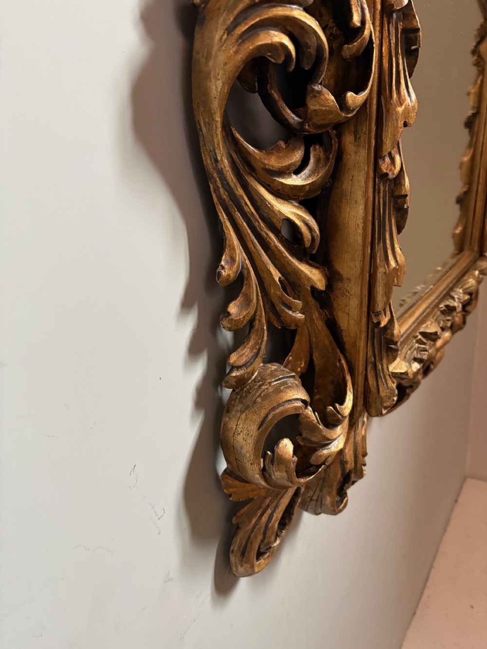 A rectangular 19th-century wall mirror set within a heavy carved giltwood frame featuring pierced scrollwork and acanthus leaf carving. View III
