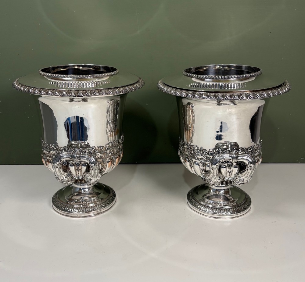 A pair of 19th-century silver-plated urn-shaped wine coolers featuring engraved crests, double scroll handles, fluted bases, and removable liners. View V