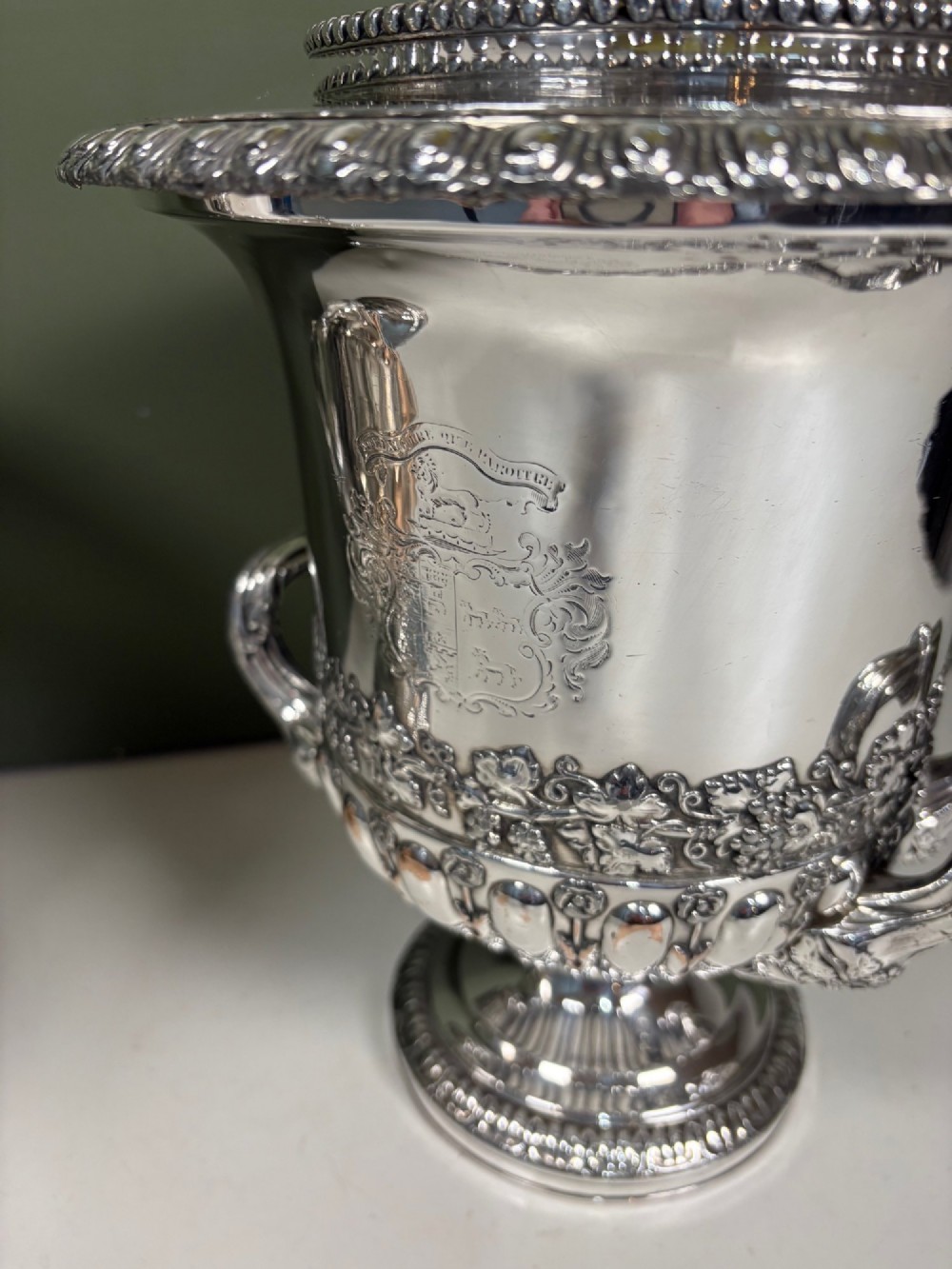 A pair of 19th-century silver-plated urn-shaped wine coolers featuring engraved crests, double scroll handles, fluted bases, and removable liners. View VI