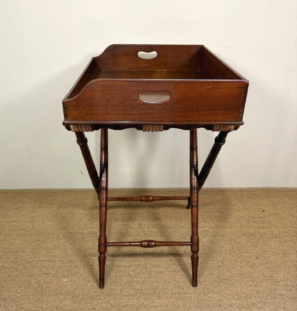 A 19th-century mahogany butlers tray with cut-out handles resting on a turned folding X-frame stand. View III