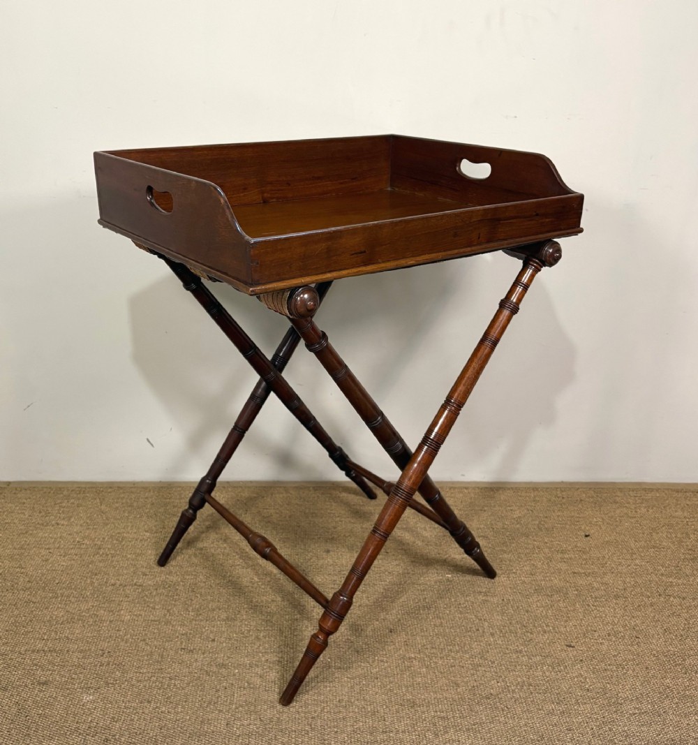 A 19th-century mahogany butlers tray with cut-out handles resting on a turned folding X-frame stand. View IV