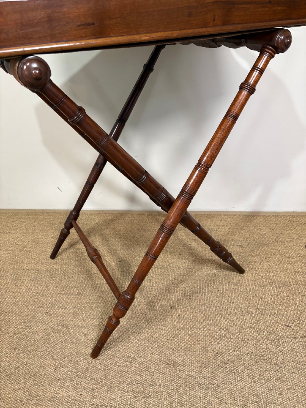 A 19th-century mahogany butlers tray with cut-out handles resting on a turned folding X-frame stand. View V