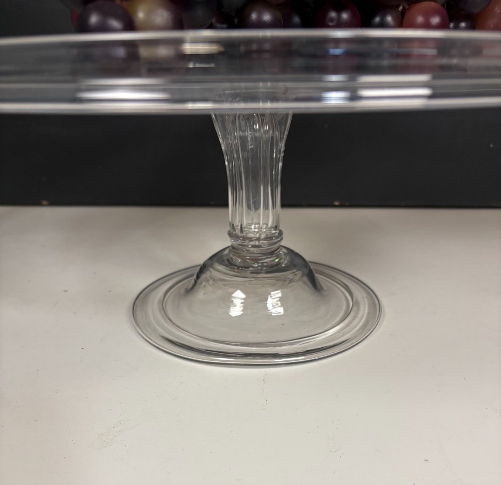A clear glass George III tazza featuring a wide circular tray supported by a turned stem and a circular footed base. View III