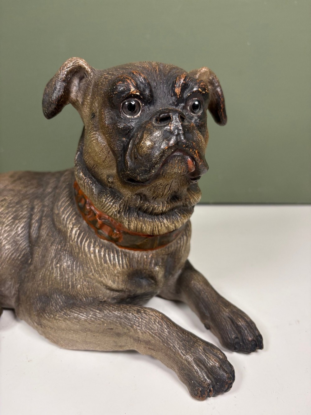 A nineteenth-century ceramic figurine depicting a reclining pug dog with a textured dark brown finish and a painted collar. View IV