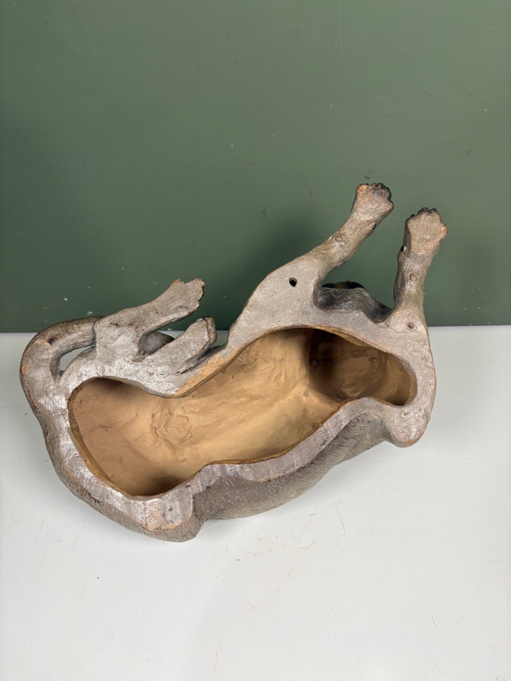 A nineteenth-century ceramic figurine depicting a reclining pug dog with a textured dark brown finish and a painted collar. View V