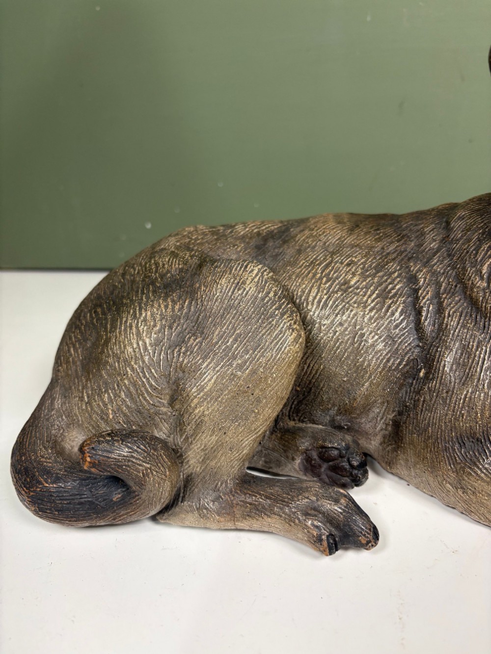 A nineteenth-century ceramic figurine depicting a reclining pug dog with a textured dark brown finish and a painted collar. View VI