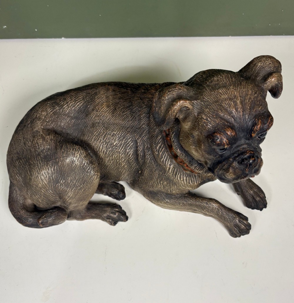 A nineteenth-century ceramic figurine depicting a reclining pug dog with a textured dark brown finish and a painted collar. View VII