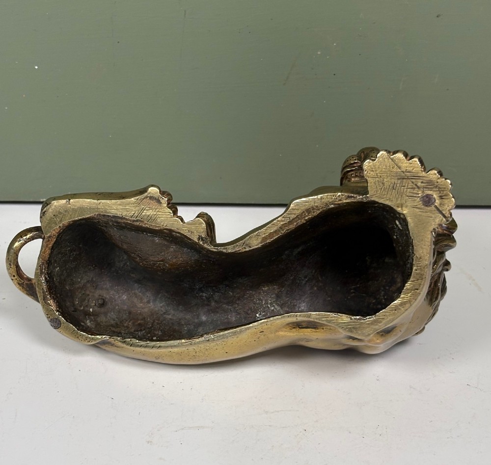 A pair of cast brass figures depicting recumbent lions with detailed manes and crossed paws facing forward. View V