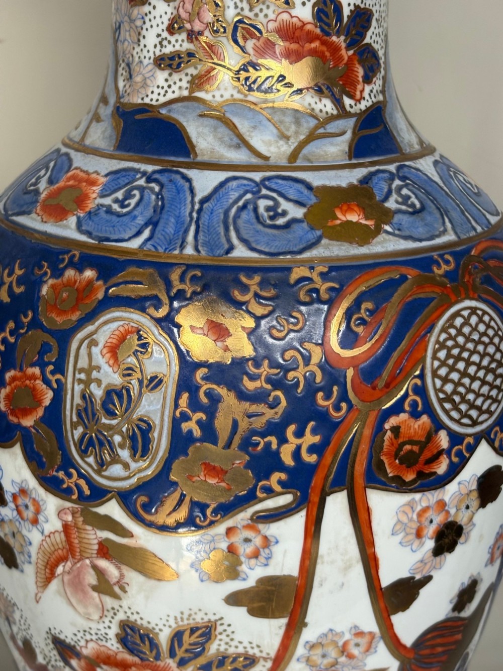 A pair of large ceramic baluster-shaped lamps decorated with traditional Japanese Imari floral patterns in blue, red, and gold, mounted on circular wooden plinths. View III