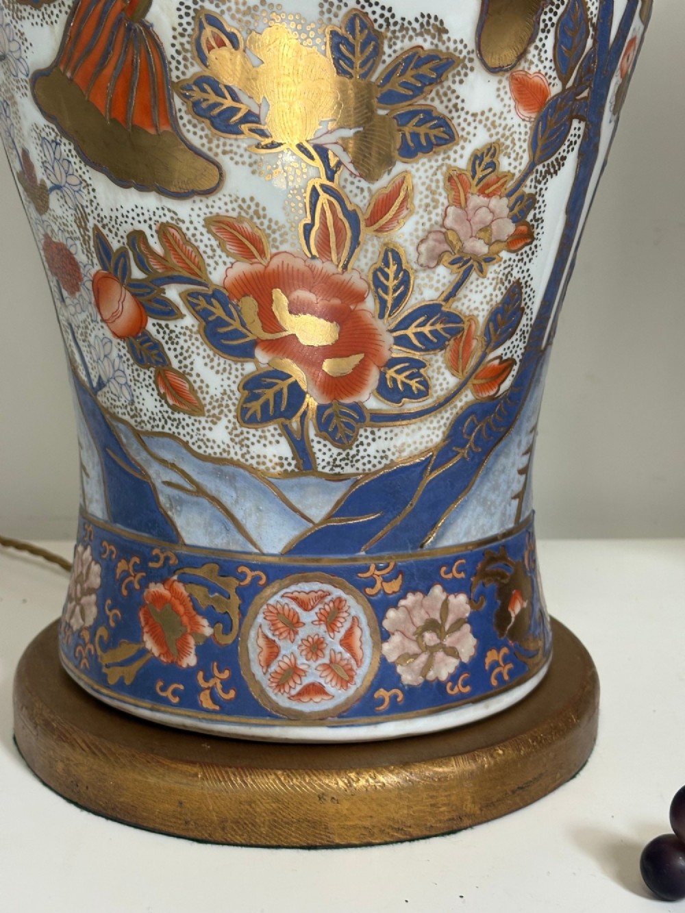 A pair of large ceramic baluster-shaped lamps decorated with traditional Japanese Imari floral patterns in blue, red, and gold, mounted on circular wooden plinths. View V